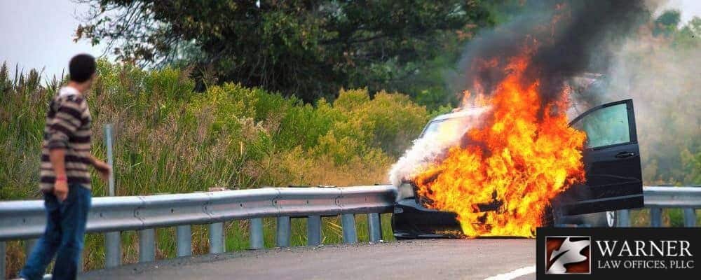 Man watching a car on fire after an accident on the highway